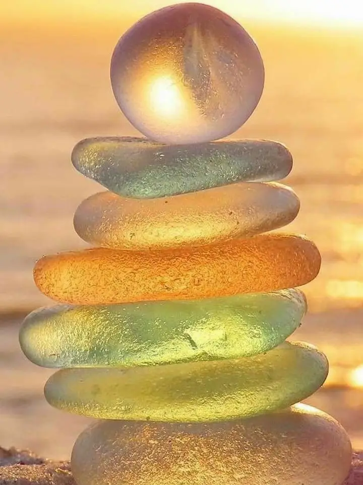  A stack of rocks with a rainbow colored light shining on it.