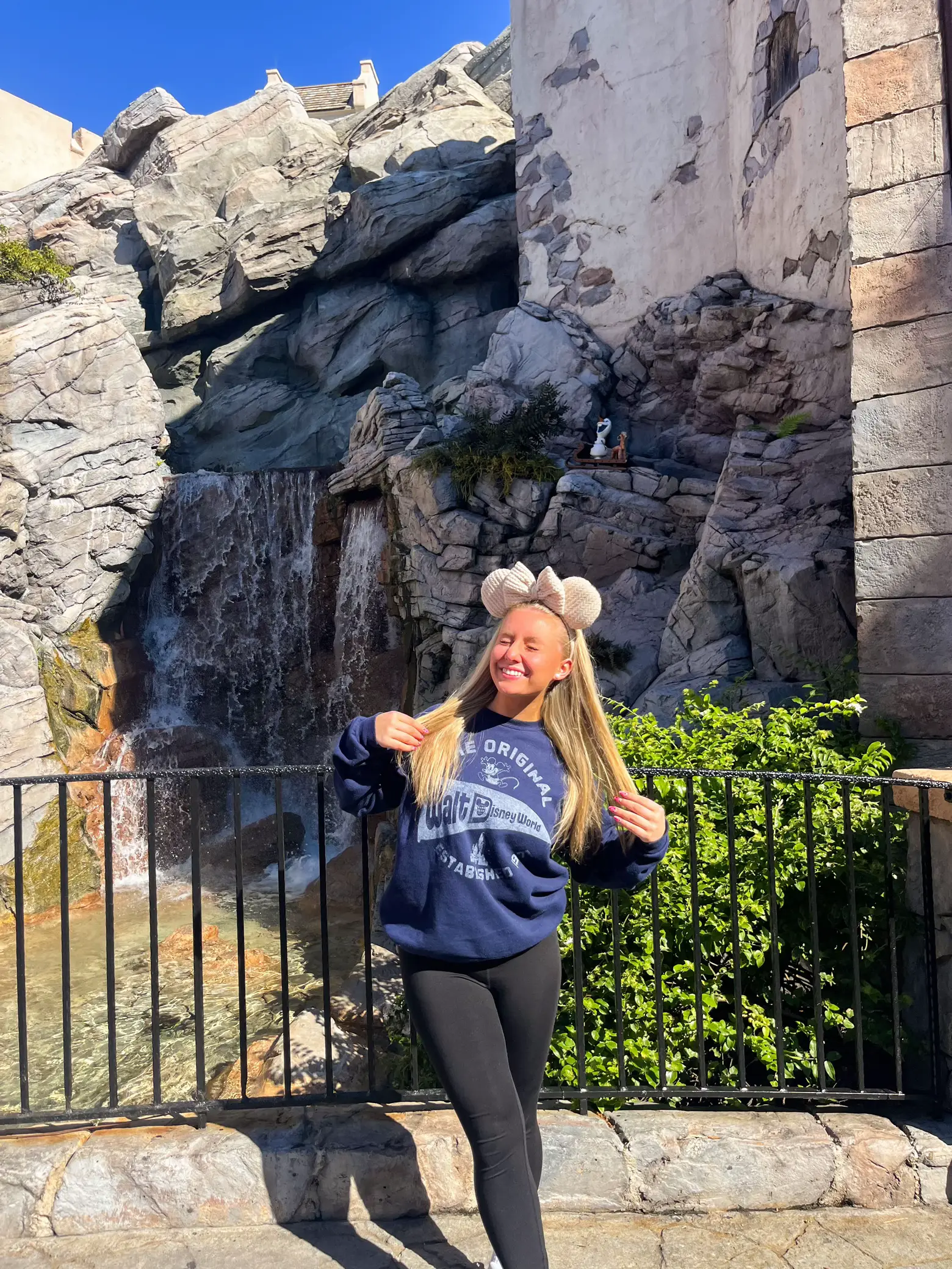  A woman wearing a World Water Park sweatshirt is standing in front of a waterfall.