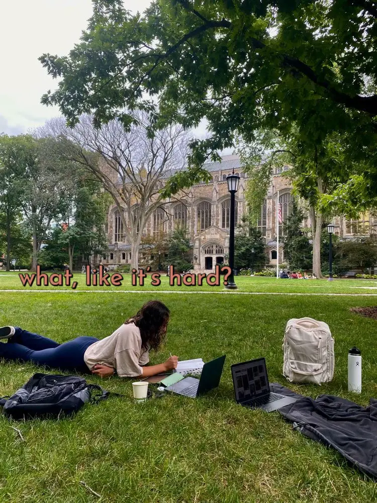  A woman is laying on the grass with a laptop on her lap.
