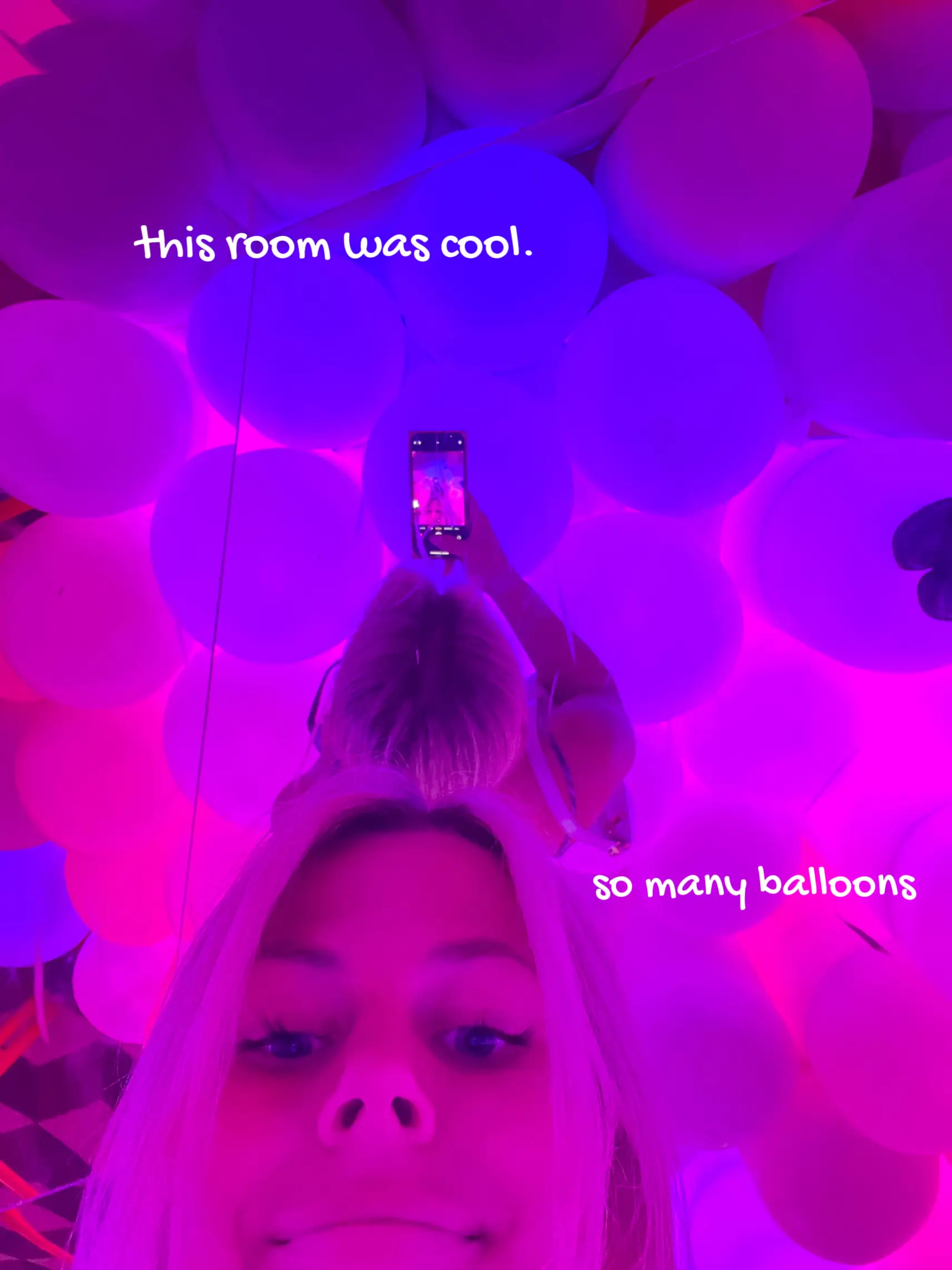  A woman is taking a selfie in a room with many balloons.