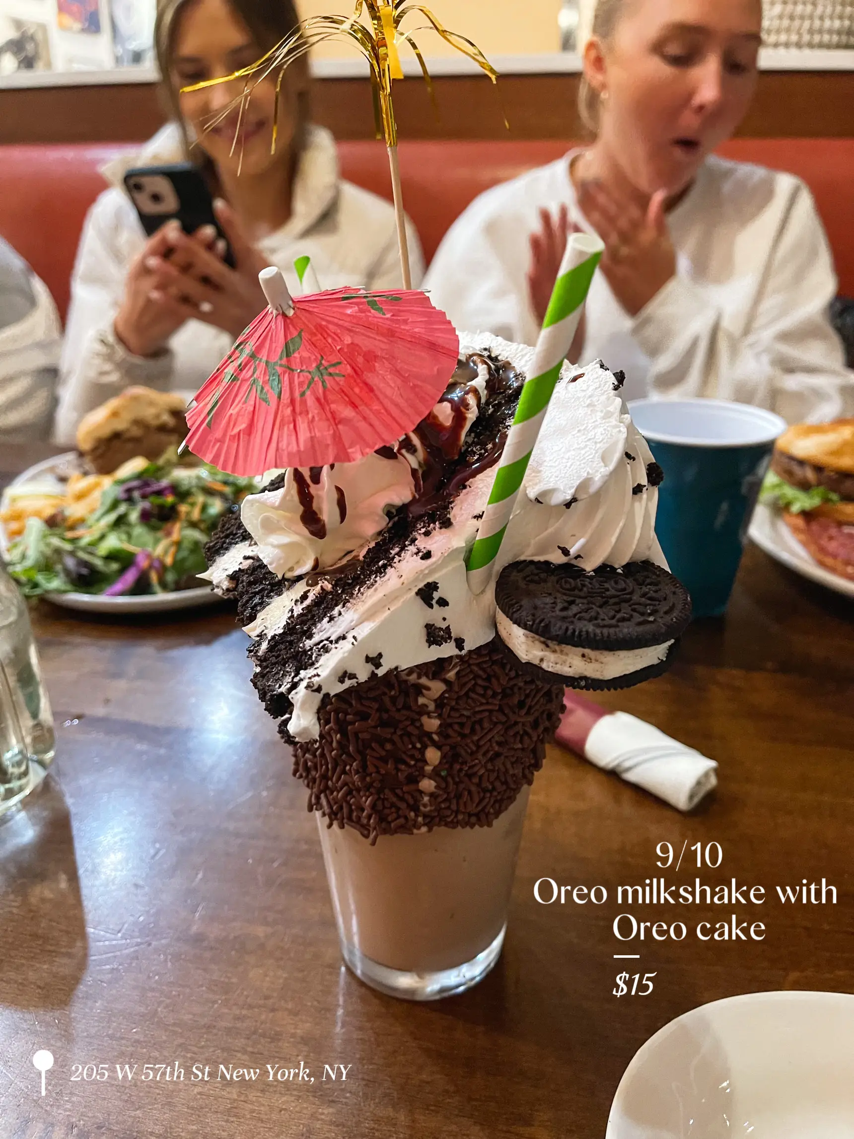  A glass of Oreo milkshake with a slice of Oreo cake on top.