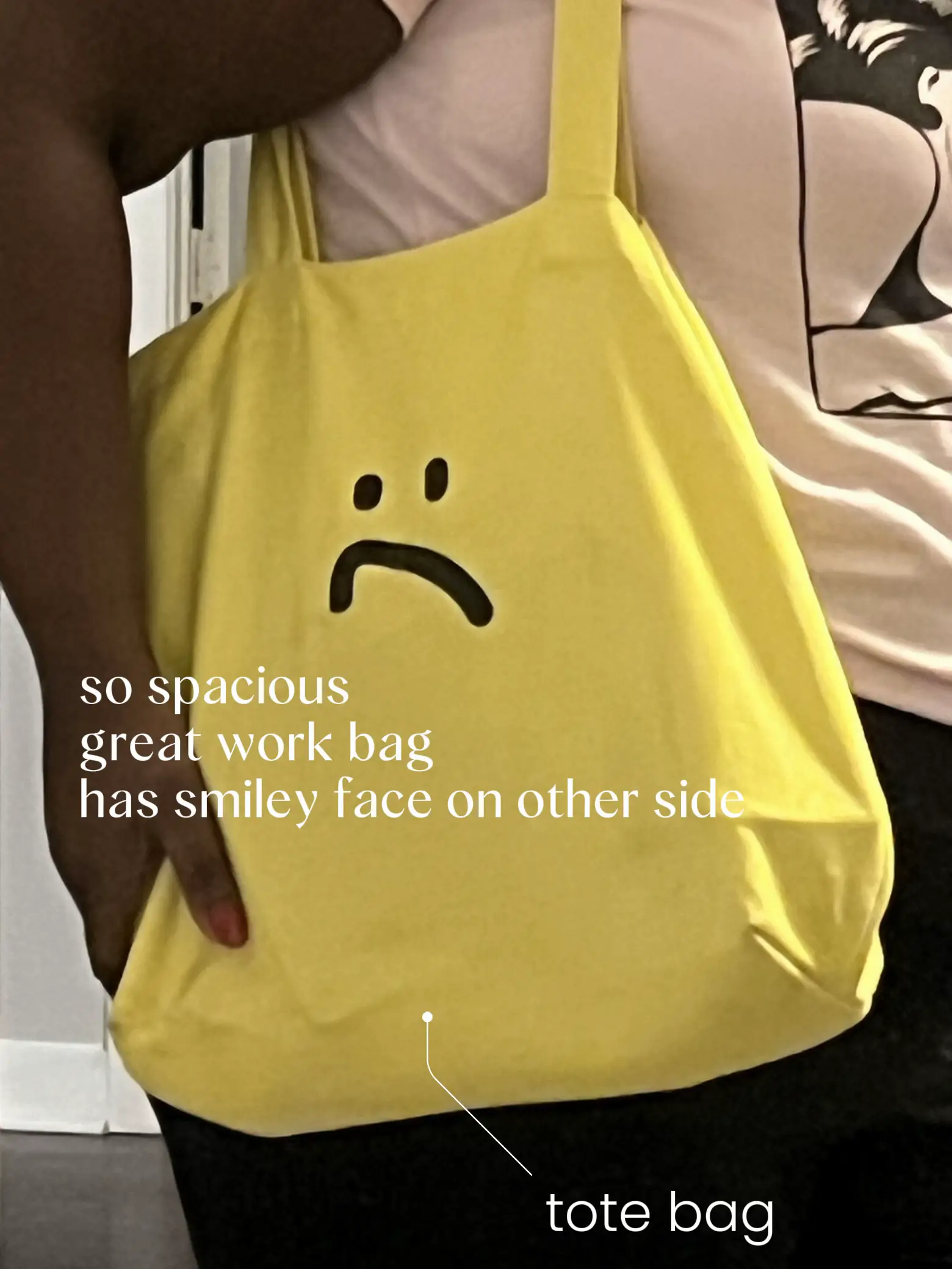  A person is holding a yellow tote bag with a smiley face on it.
