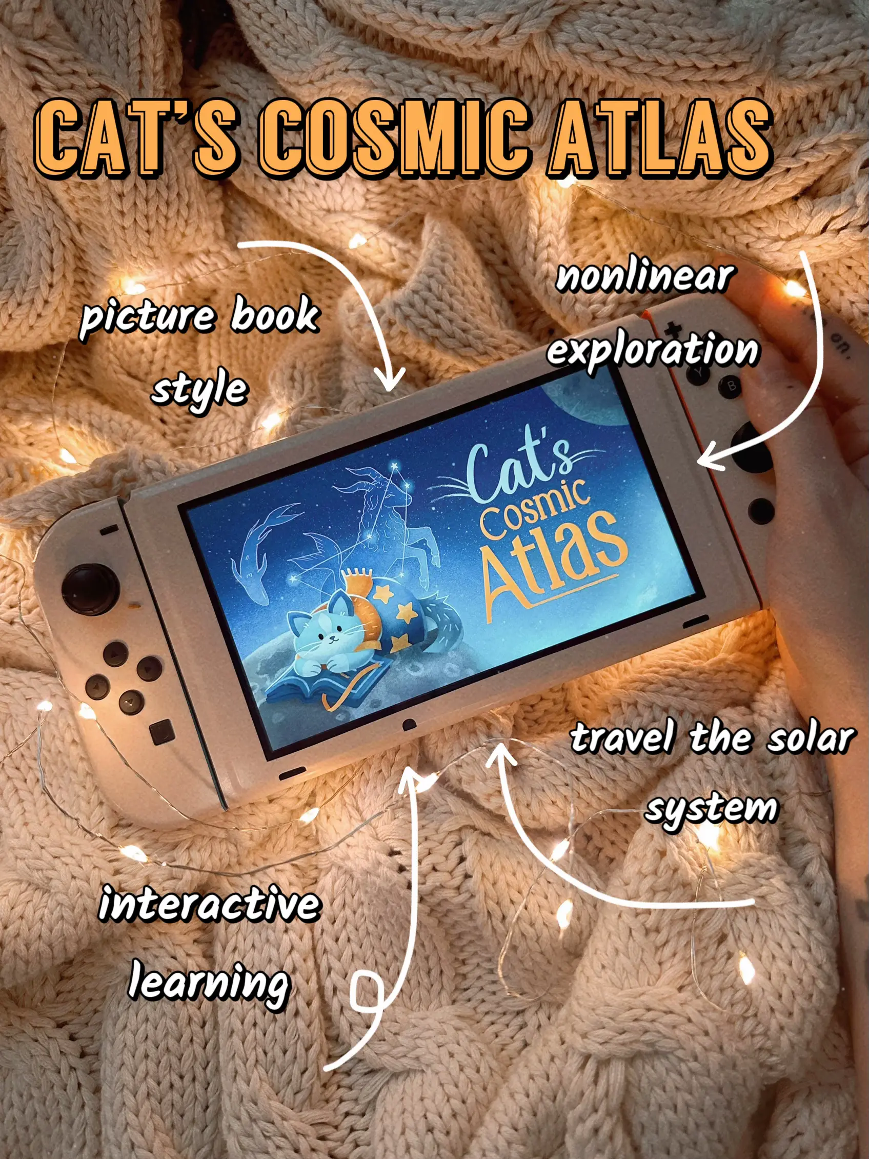  A hand holding a Nintendo Wii controller with a screen that says "Cats Cosmic Atlas".