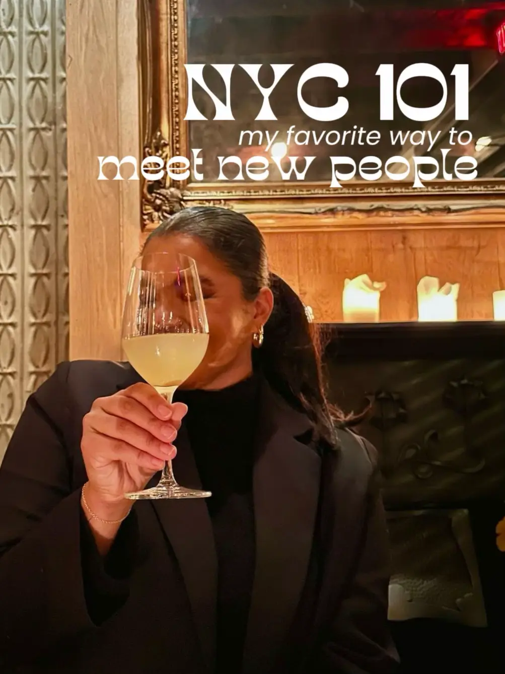  A woman in a black jacket is holding a glass of wine in front of her face.