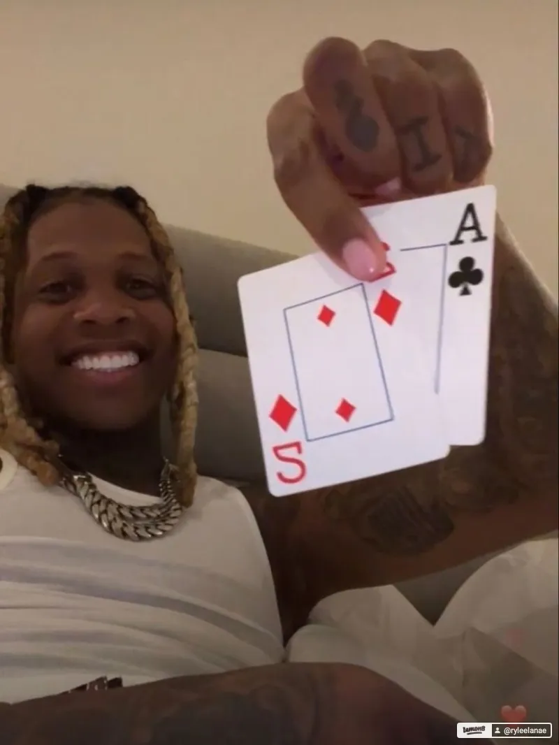  A man with a tattoo on his arm is holding a card with a number on it.