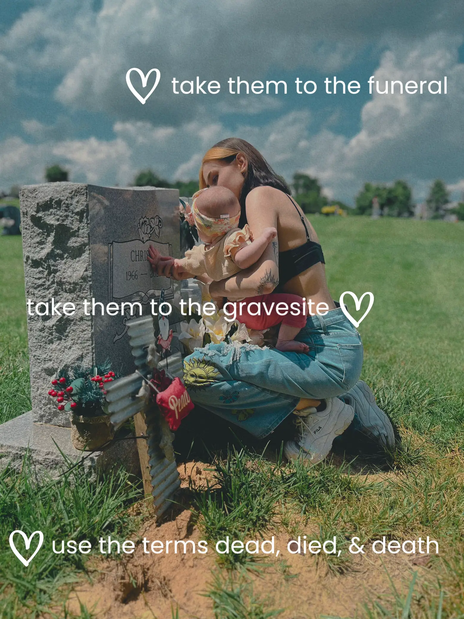  A woman is sitting in front of a gravesite, holding a baby.
