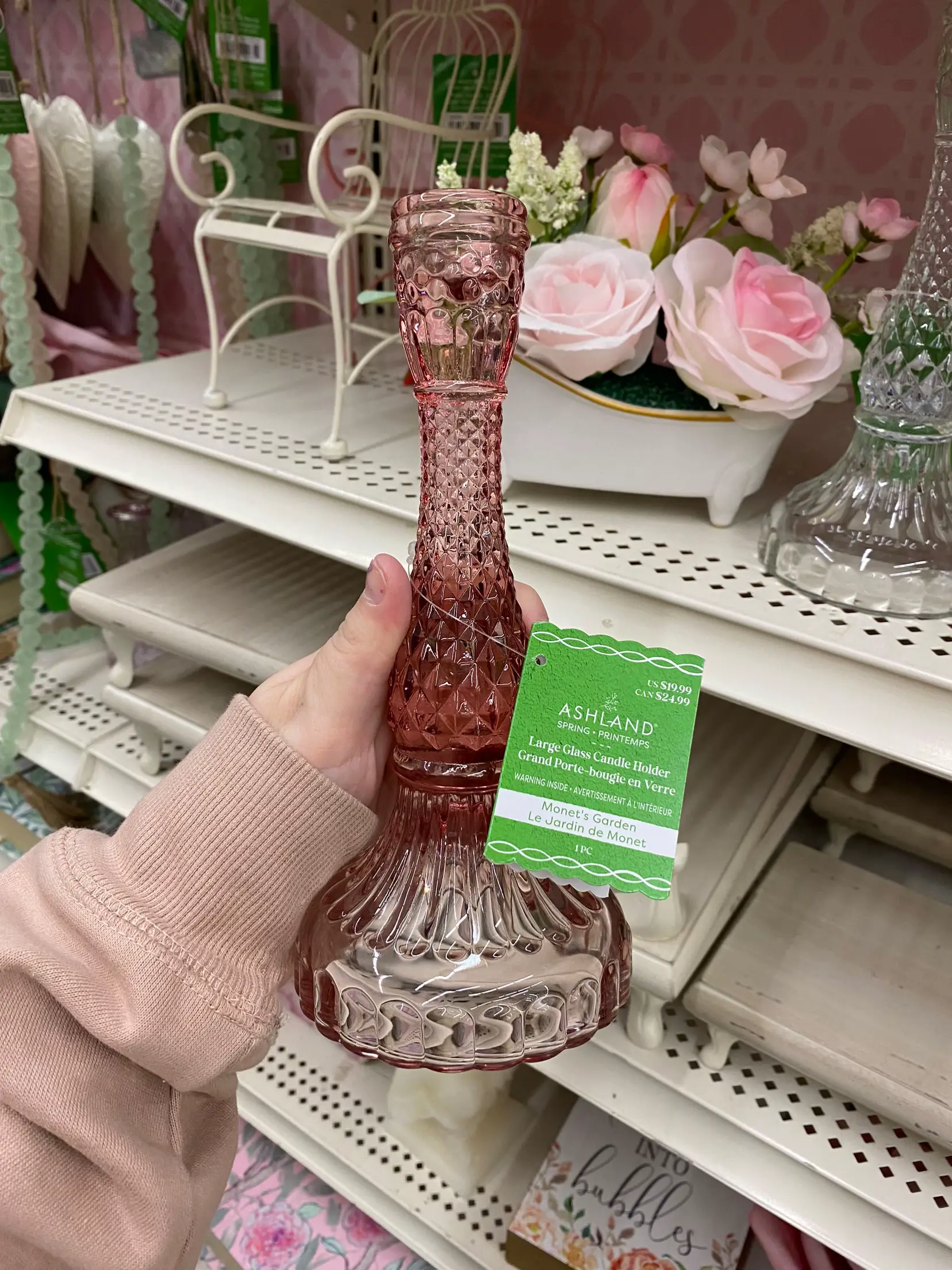  A hand holding a pink glass vase.
