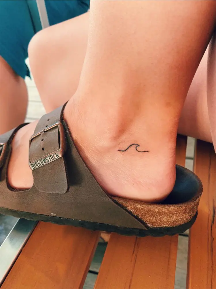  A person with a tattoo on their foot is wearing sandals.