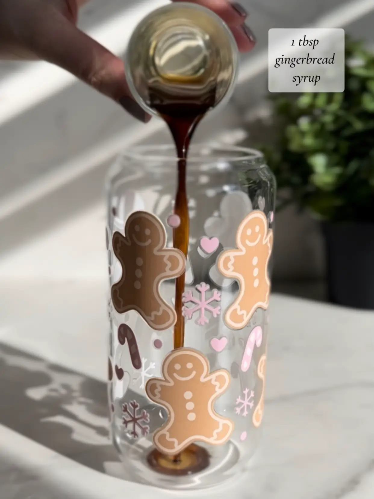  A person is pouring gingerbread syrup into a glass jar.