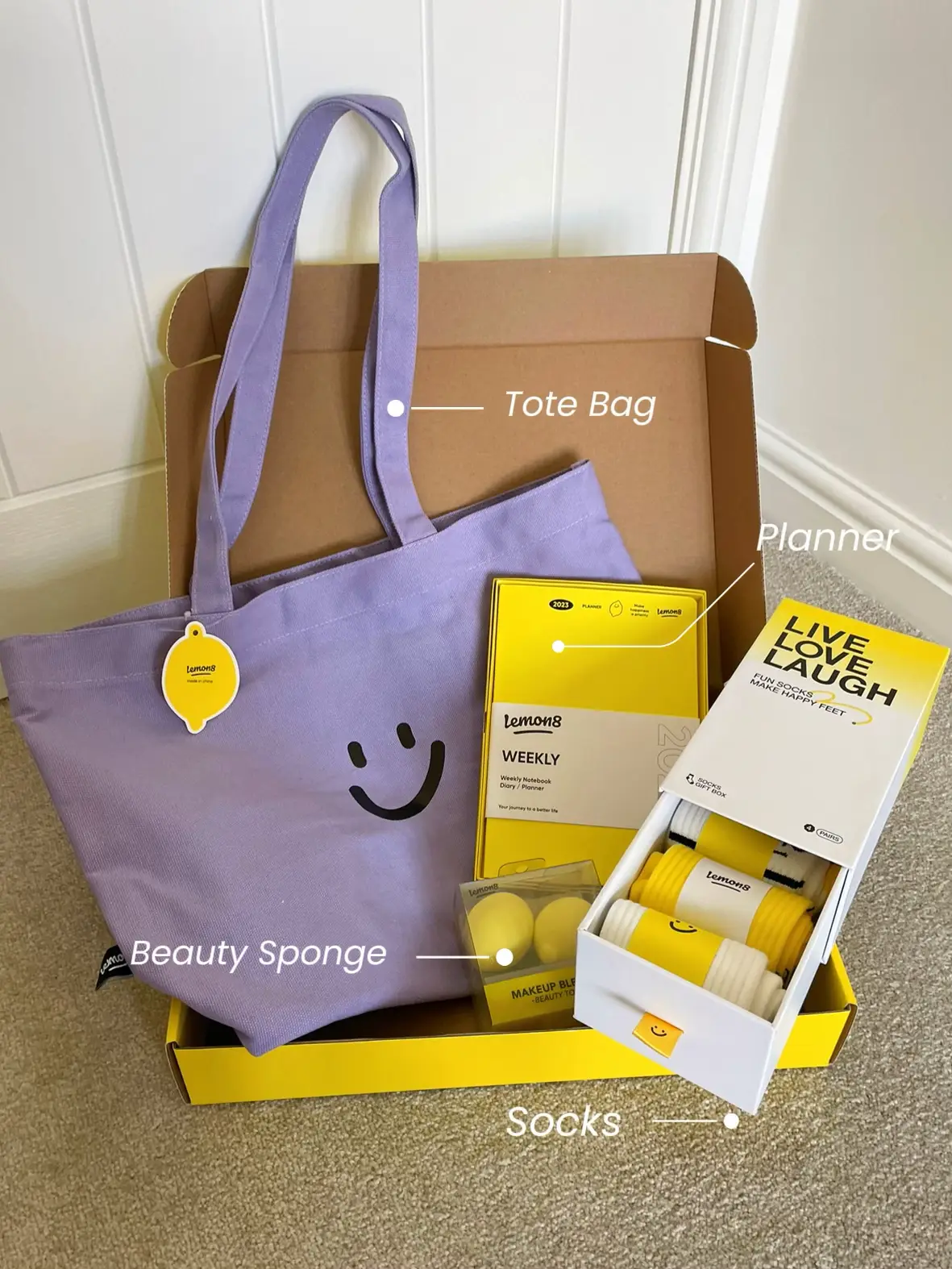  A box of makeup and a tote bag with a smiley face on it.
