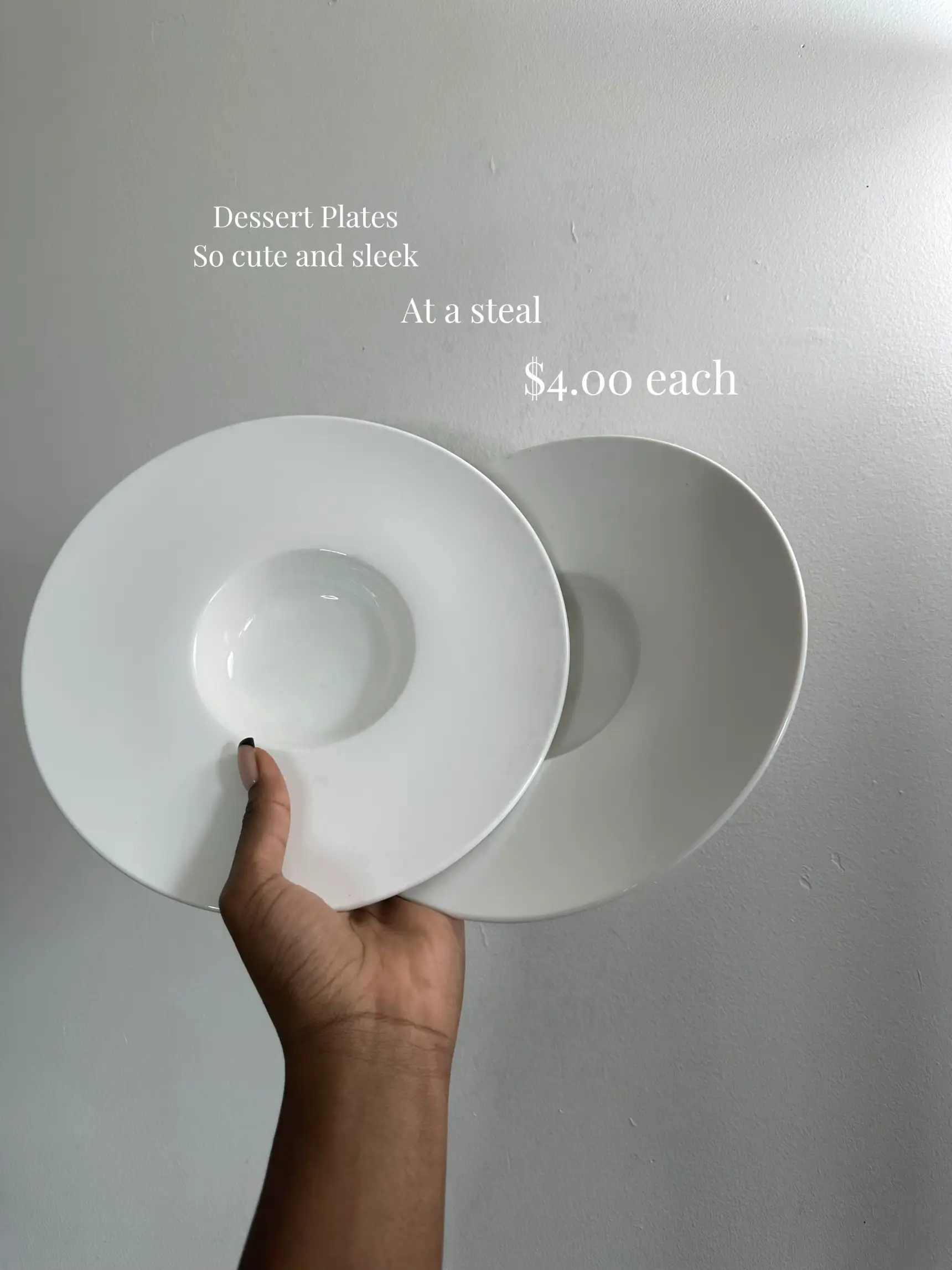  A hand holding three white plates with shadows on them.
