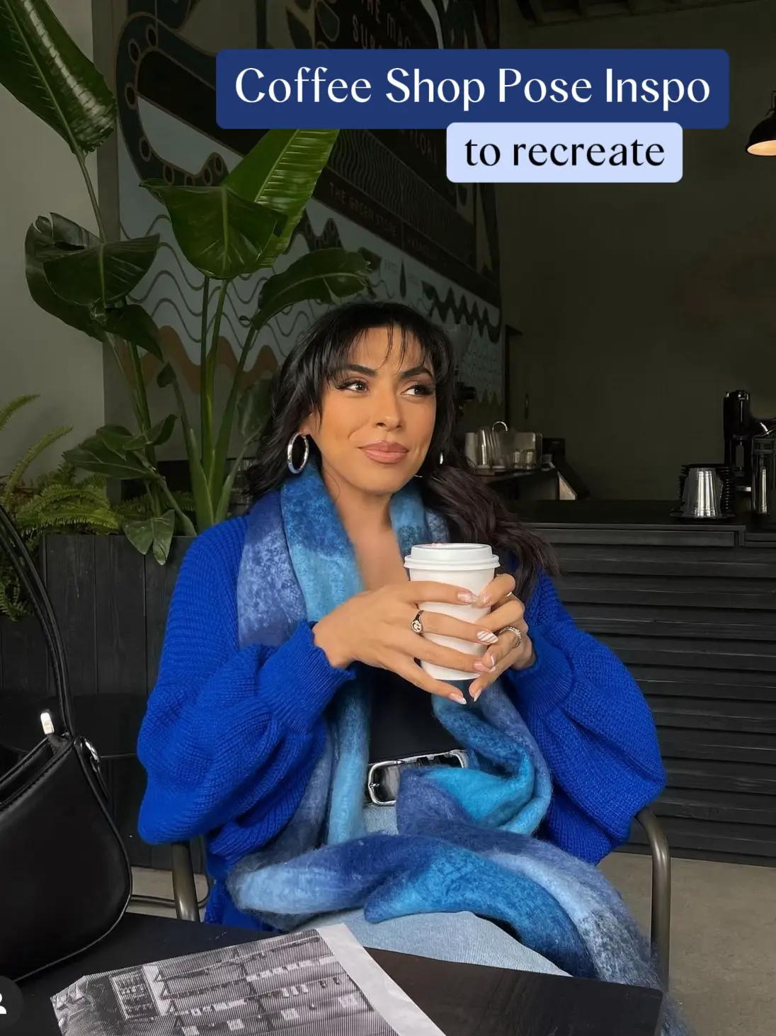 A woman in a blue sweater is sitting at a table with a cup of coffee.