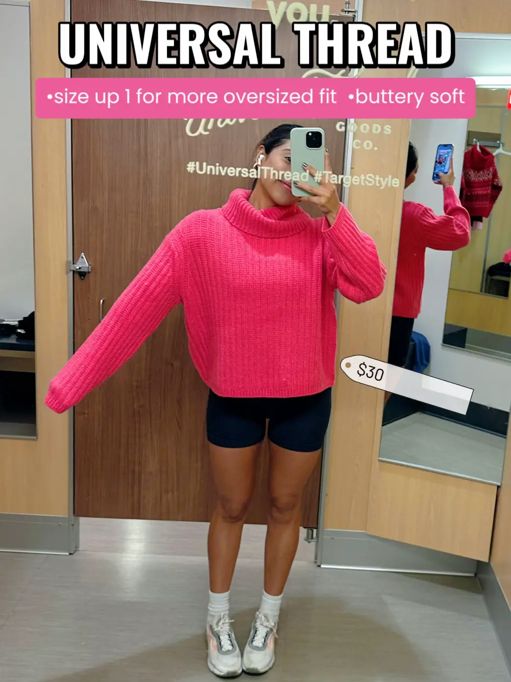  A woman in a pink sweater is taking a selfie in a mirror.