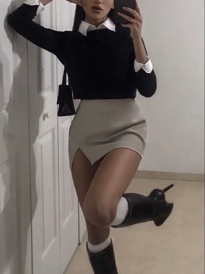  A woman wearing a black shirt and white skirt is taking a selfie.